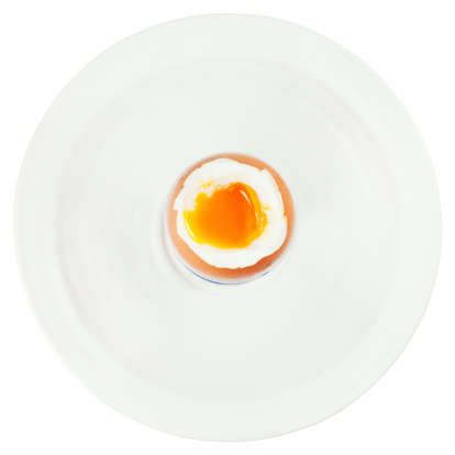 top view of soft boiled egg in egg cup on white plate isolated on white