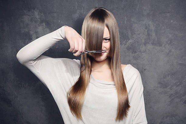 Young woman with scissors trimming her bangs