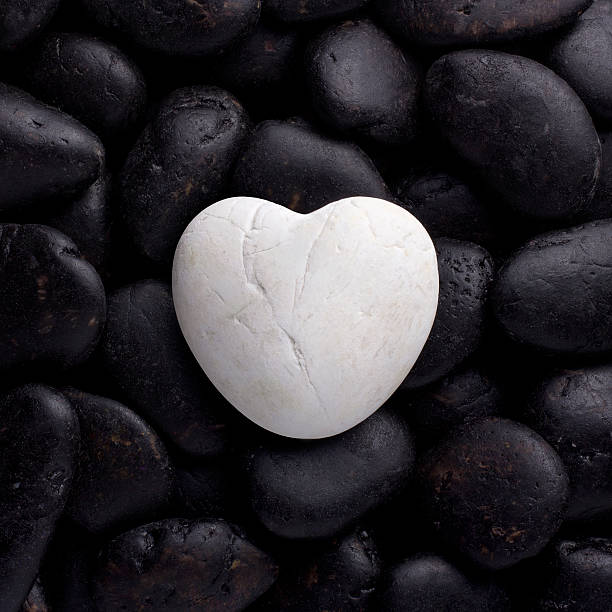 istock White rock, stone in heart shape on pile black pebbles 178723459