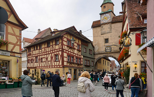 Rothenburg ob der Tauber, Germany - October 20, 2023: People going near historical buildings at Rothenburg ob der Tauber - old fortified city in Germany.