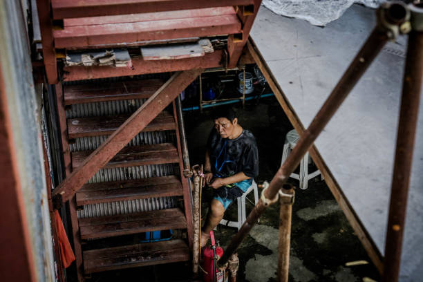 Someone does chores inside of a workers' camp in Bangkok, Thailand on November 11, 2023. Over 100 people, including migrant workers, live and work here 7 days per week. These camps are home to thousands of Thai, Burmese, and Cambodian construction workers and their families.