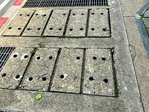 a grate covered in holes on the sidewalk.