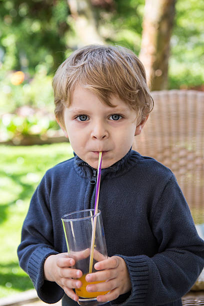 istock Happy little boy drinking orange juice with straw 178728140