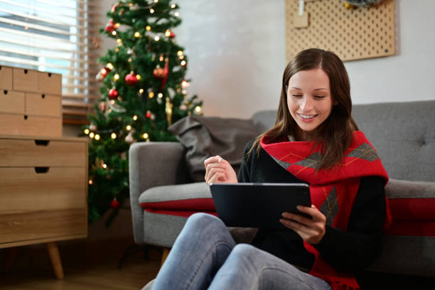 istock Caucasian female freelancer using digital tablet while sitting in living room with beautiful Christmas tree 1787281547