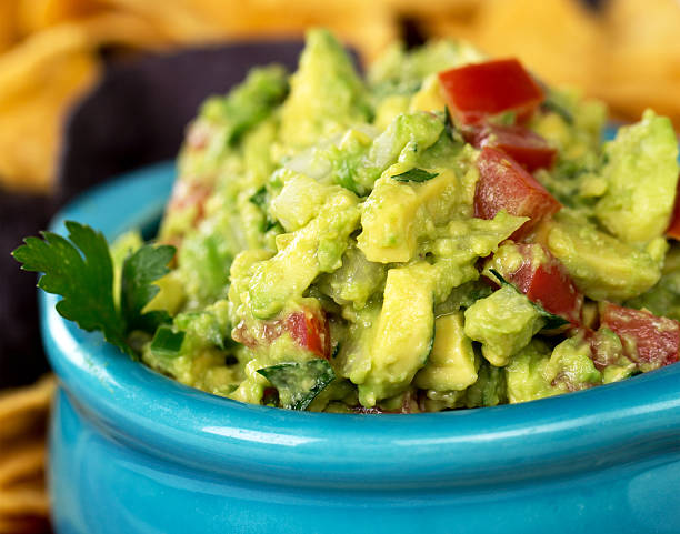 Guacamole A bowl of fresh guacamole with corn tortilla chips. Intentional shallow depth of field. guacamole stock pictures, royalty-free photos & images