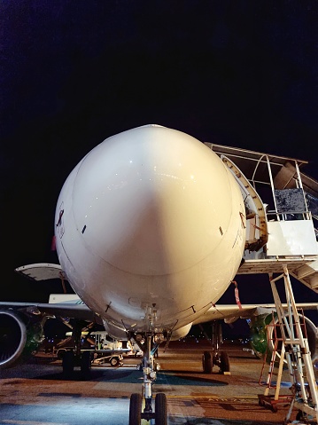 Surabaya, Indonesia - Nov 08, 2023: White airplane nose parked at the airport depicted from front side with dark night as the background