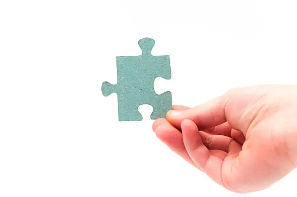 hands holding a puzzle piece on a white background