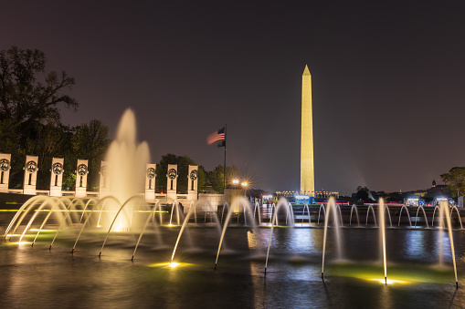 Washington DC, United States - July 27, 2023: World War II Memorial at nighttime with the Washington Monument in the background