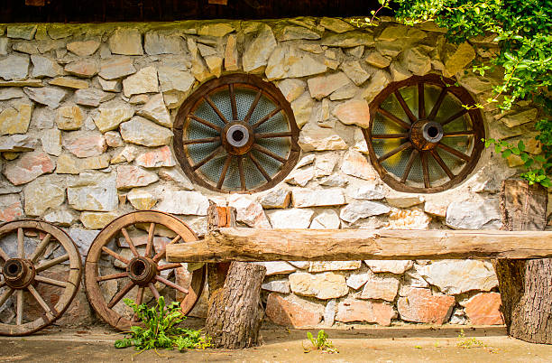 Old wooden wheels of cart at a barn wall.