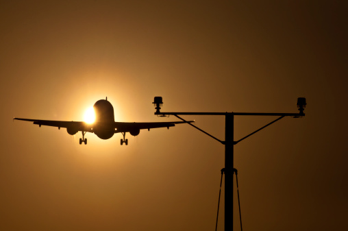 Passenger jet approaching runway at sunset