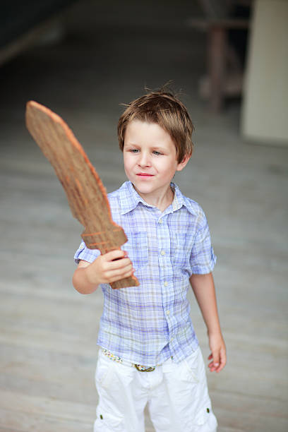 Casual outdoor portrait of little boy with wooden sword