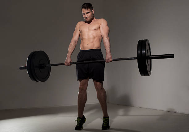 male athlete performing clean and jerk with barbell Fit male athlete using the technique clean and jerk to lift a heavy barbell. He wears black pants. clean and jerk stock pictures, royalty-free photos & images