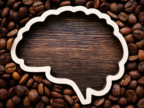 Brain outline with space for inscription surrounded by coffee beans for energy and cheerfulness.