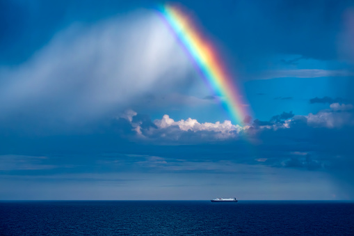 A rainbow with a side rainbow on the horizon during a storm with raindrops and gray sky