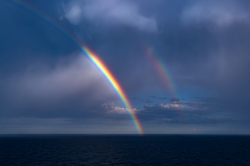 A rainbow with storm clouds forms over the horizon in the Mediterranean Sea.