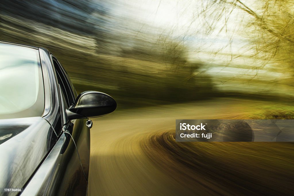 Motion image of black car making turn Side view of black car in turn with heavy blurred motion. Blurred Motion Stock Photo