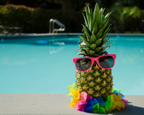 Funny pineapple in sunglasses by the pool