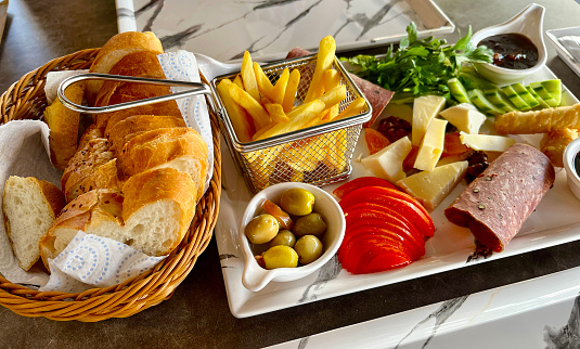 Turkish breakfast consisting olives, tomato, fries, salami, cheese, cucumber, salad, leaves