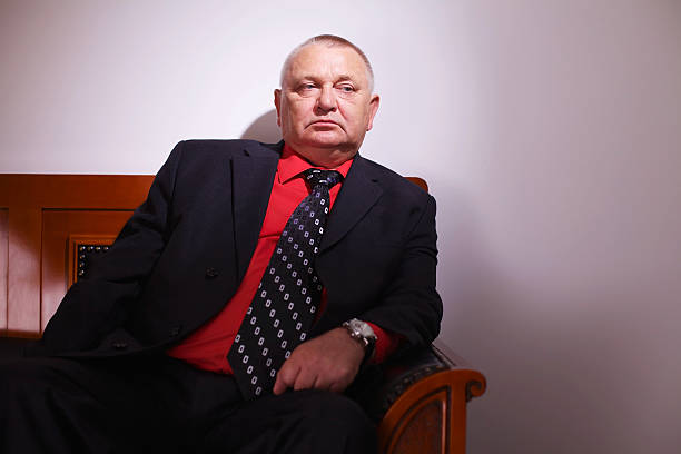 Pensive senior businessman Serious middle aged businessman in black suit sitting on leather sofa in office indoor godfather godparent stock pictures, royalty-free photos & images