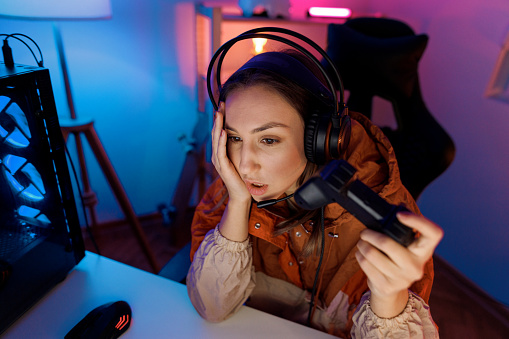 Young beautiful woman upset about online game loss while playing video games at home