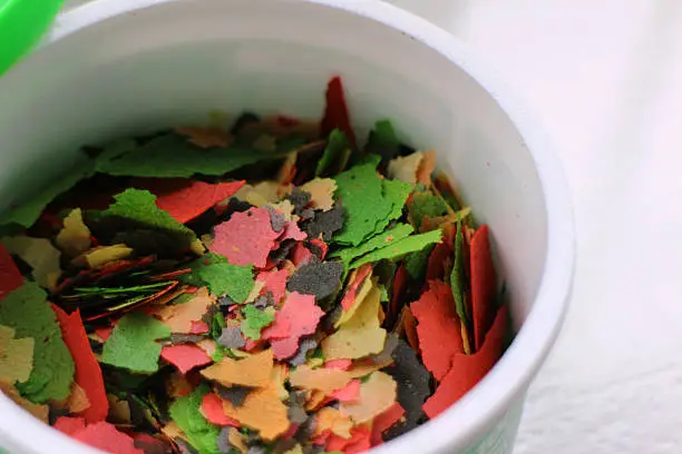 A pot of brightly coloured fish food flakes.