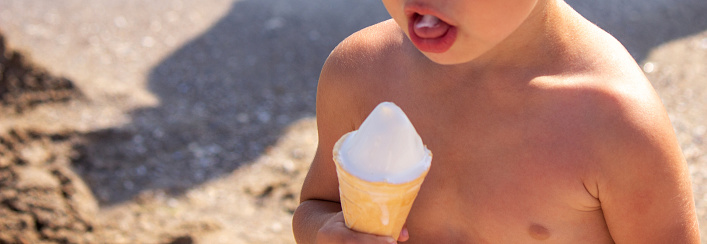 little boy eating ice cream on the beach on vacation. sea