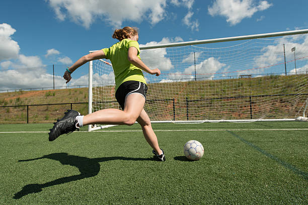 Female soccer player Young adult female soccer player practices shots on goal on a beautiful turf field high school stock pictures, royalty-free photos & images