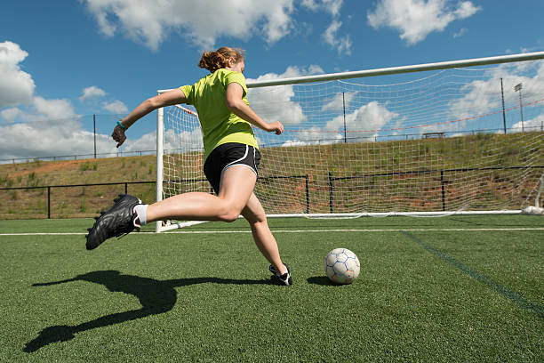 Female soccer player Young adult female soccer player practices shots on goal on a beautiful turf field high school soccer stock pictures, royalty-free photos & images