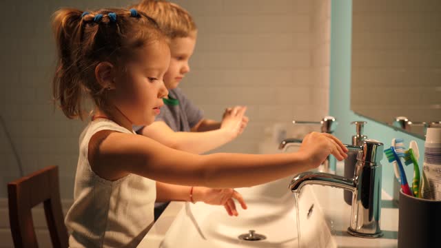Sister and brother children in bathroom washing hands in evening family at home