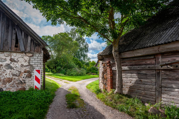istock Rural road runs between two barns. A road junction and directional sign are visible. Stende Manor, Latvia. 1787419812