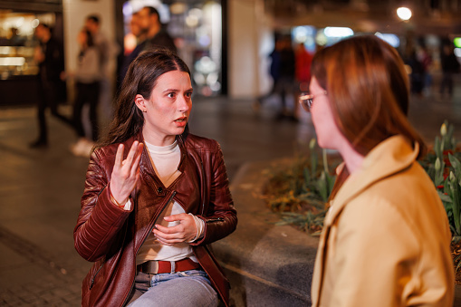 Experience the magic of a nighttime sign language exchange as two friends share stories and experiences on a quiet street bench