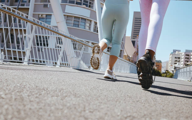 女性は街でワークアウトし、フィットネスレッグスランニングシューズを履き、マイアミのストリートでステップマラソンのモチベーションを高めています。夏に一緒にトレーニングする友� - marathon sport sports training city street ストックフォトと画像