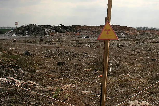sign warning about the zone contaminated by radiation on the background of the contaminated soil