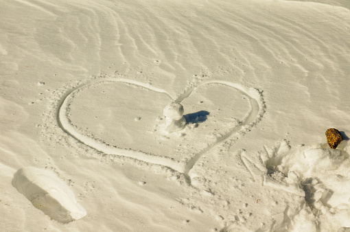 Silhouette of a heart in the snow on a background of a cloudy sky