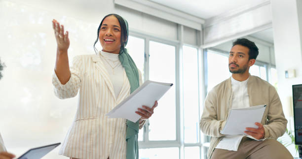 istock Business, woman and speaker pointing in training, workshop or conversation for feedback, target growth or goals. Talking, mentor or presentation on paper, documents or tech in teamwork collaboration 1787527362