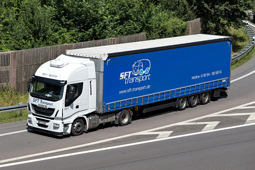Wiehl, Germany - June 25, 2019: SFT Transport Ivceo Stralis truck with curtainside trailer on motorway