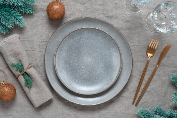 istock Christmas minimal table setting. Empty gray plates, gold cutlery, glasses and Christmas decorations. Top view, selective focus. 1787541162