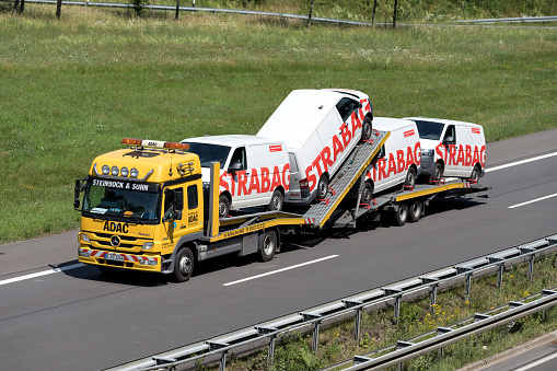Wiehl, Germany - June 25, 2019: ADAC Mercedes-Benz Atego car-carrying truck loaded with Strabag vans on motorway