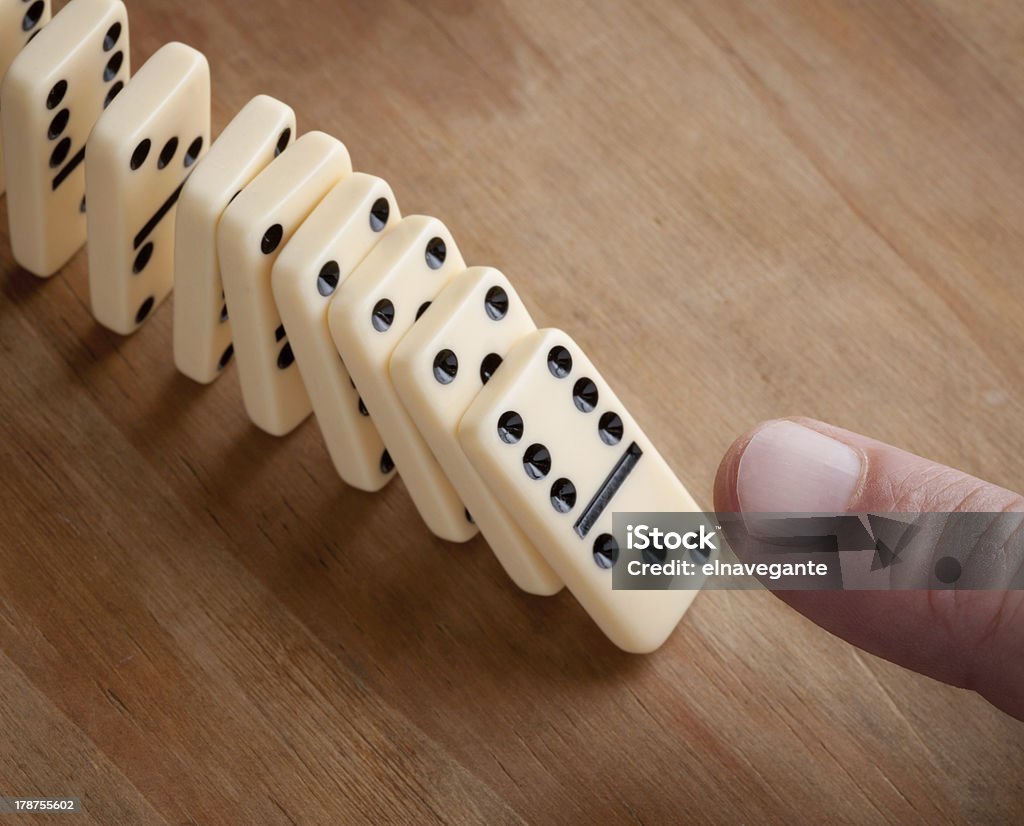 Finger pushing domino pieces Finger pushing line of domino pieces Adult Stock Photo