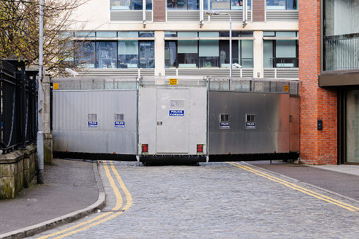 A metal mobile Police Cordon barrier blocks off a street in Belfast during a parade.