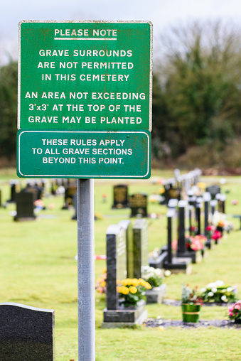 Sign in a lawn cemetery reminding people that grave surrounds are not permitted.