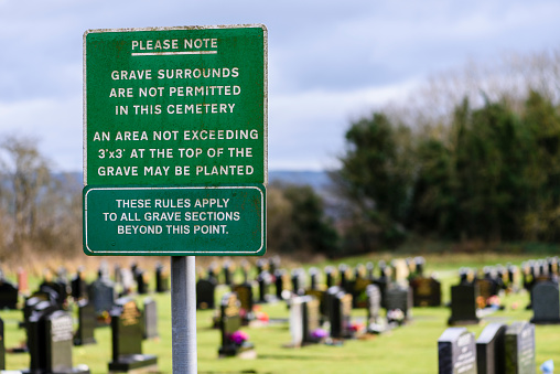 Sign in a lawn cemetery reminding people that grave surrounds are not permitted.