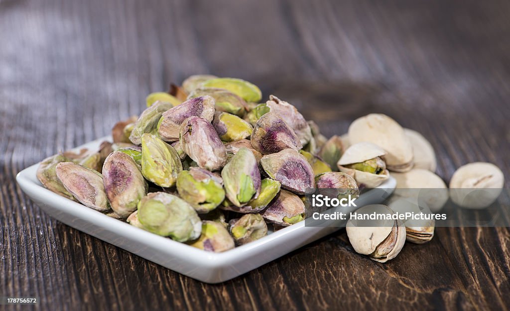 Pistachios in a bowl (on wood) Pistachios in a bowl on wooden background Appetizer Stock Photo