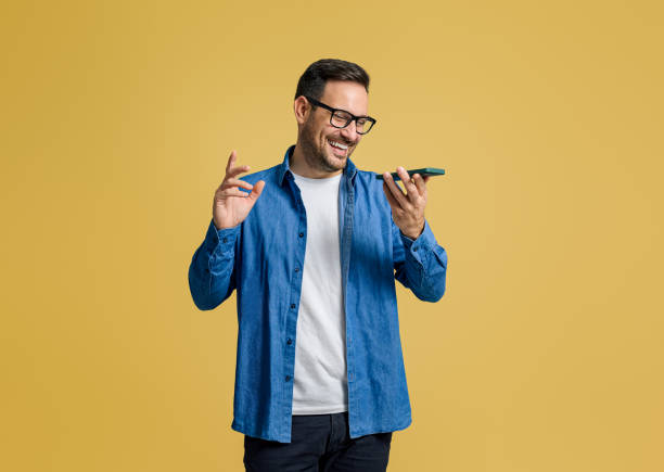 istock Cheerful handsome entrepreneur sending voice mail over mobile phone on isolated yellow background 1787566567