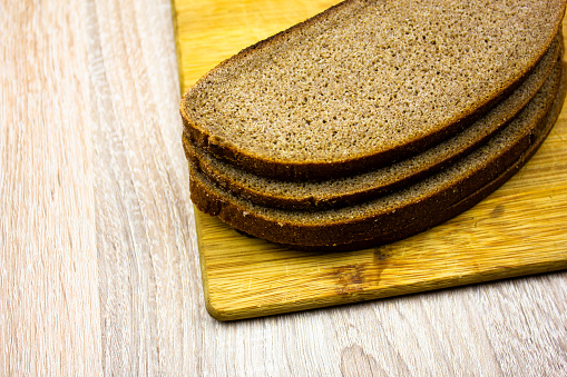 Slices of bread on a wooden board. Sliced bread, pastries.