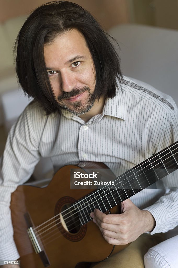 Man holding a guitar Portrait of a smiling man sitting down, holding a guitar. Acoustic Guitar Stock Photo