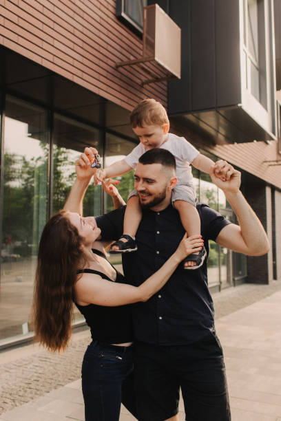 Happy married couple with son celebrating moving in new house home, demonstrating keys, standing in apartment, real estate mortgage concept. Focus on keys, held by excited young spouses homeowners. feliz pareja casada con hijo que celebra la mudanza en la nueva casa de la casa, demostrando las llaves, de pie en el apartamento, concepto de hipoteca inmobiliaria. concéntrese en las llaves, sostenidas por cónyuges jóvenes emocionados propietarios de