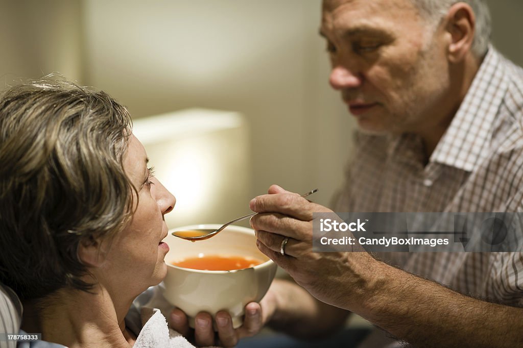 Caring senior man feeding his sick wife Caring senior man feeding his sick wife with warm soup Feeding Stock Photo