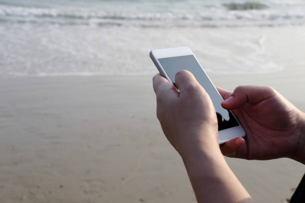 istock Closed up hand holding smartphone and touch screen for online with internet on the beach and seaside for business trip. Vacation and relaxation with technology on holiday concept 1787587674