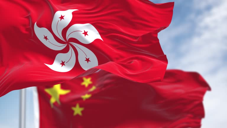 Flags of Hong Kong and China waving in the wind on a clear day